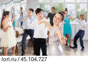 Teen girl in elegant evening dress dances incendiary twist with boy partner during choreography lesson. Стоковое фото, фотограф Яков Филимонов / Фотобанк Лори