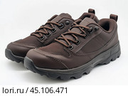 Dark brown leather lace-up running shoes with low tops, thick soles. The laces and black rubber outsole. Sporty look. Men to wear during outdoor activities, hiking. Brown shoes. Trendy Male Boots Pair. Стоковое AI-изображение, AI-художник Марина Демидюк / Фотобанк Лори