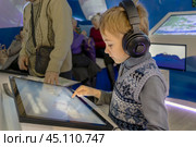 Immersion in world of technology: child wearing headphones in front of an interactive screen. Стоковое фото, фотограф Алла Чесноковва / Фотобанк Лори