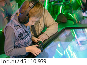 Boy wearing headphones and holding gamepad with his father explores technology on an interactive screen. Стоковое фото, фотограф Алла Чесноковва / Фотобанк Лори