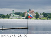 Российский флаг на фоне православного монастыря. Антониево-Сийский монастырь (2024 год). Стоковое фото, фотограф Яковлев Сергей / Фотобанк Лори