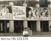 Молодые мужчины на фоне афиш у входа в кинотеатр. ГДР. 1960-е годы. Стоковое фото, фотограф Retro / Фотобанк Лори