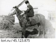 Мужчина в меховой шапке сидит верхом на лошади в сельской местности. 1970-е годы. Стоковое фото, фотограф Retro / Фотобанк Лори