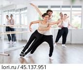 Positive duet of gymnasts rehearsing performance with support, modern ballet dancers in pair during group training session in ballet hall. Стоковое фото, фотограф Яков Филимонов / Фотобанк Лори
