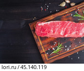Raw meat, beef steak with seasoning on chopping board on dark background with rosemary, Стоковое фото, фотограф Natalia Gdovskaia / Фотобанк Лори