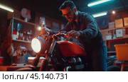A man works diligently on customizing a motorcycle in a dimly lit workshop during the evening hours. Стоковое AI-изображение, AI-художник Сергей Толмачёв / Фотобанк Лори