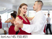 Woman in red enjoying slow foxtrot with partner in dance studio. Стоковое фото, фотограф Яков Филимонов / Фотобанк Лори