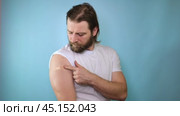 Successful Covid-19 Vaccination. Vaccinated Man Gesturing Okay And Showing Arm With Bandage After Vaccine Injection, Posing Wearing Antiviral Protective Face Mask, blue Background. Стоковое видео, видеограф Марина Демидюк / Фотобанк Лори