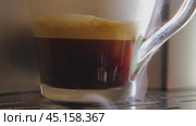 A close-up of a glass cup filled with freshly brewed cappuccino. The drink is dark brown in colour and has a layer of foam on top. Steam is rising from the cup. Стоковое видео, видеограф Воловодов Владимир / Фотобанк Лори
