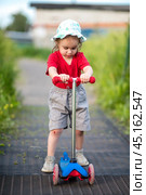 Little girl on scooter with scraped knees on walk. Стоковое фото, фотограф Анна Никонорова / Фотобанк Лори