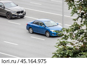 Two cars in motion on city street. Toyota corolla and BMW X5 racing at high speed on urban avenue. Compliance with speed limits on the road. Редакционное фото, фотограф Константин Григорьев / Фотобанк Лори