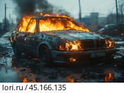 A car on fire standing on the street after riots or pogroms. Bright tongues of flame burst out of the car, and thick black smoke rises into the sky. The asphalt around is covered with puddles reflecting orange glare from the fire. The car is in a completely destroyed state, traces of chaos and devastation are visible around. The atmosphere in the photo conveys an extreme situation associated with riots and violence on the streets. Стоковое AI-изображение, AI-художник Анна Кривицкая / Фотобанк Лори