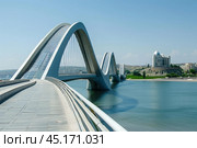 Modern pedestrian bridge spanning over river in city. Стоковое AI-изображение, AI-художник Иван Рябоконь / Фотобанк Лори