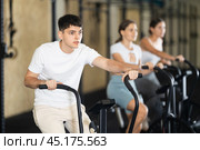 Young guy exercising on exercise bike in gym. Стоковое фото, фотограф Яков Филимонов / Фотобанк Лори