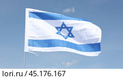 Large flag of Israel fixed on metal stick waving against background of clear sky during daytime. Стоковое видео, видеограф Яков Филимонов / Фотобанк Лори