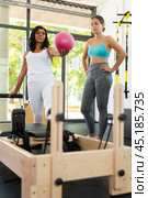 Woman coach helping young woman in pilates workout with ball. Стоковое фото, фотограф Яков Филимонов / Фотобанк Лори