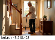 In a cozy, well-lit home, an elderly person using a cane is helped by a caregiver to climb a staircase fitted with support rails. The room feels warm and inviting, with sunlight streaming through the window, showcasing the care and attention given to ensure the elderly person's safety and comfort. Стоковое AI-изображение, AI-художник Ирина Старикова / Фотобанк Лори