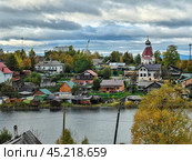 A picturesque view of Kandalaksha on the Kola Peninsula with colorful houses and serene waters reflecting the autumn sky. Редакционное фото, фотограф Александра Селина / Фотобанк Лори