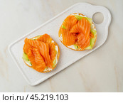 Two open sandwiches with salmon, cream cheese, cucumber slices on white marble table. Стоковое фото, фотограф Natalia Gdovskaia / Фотобанк Лори