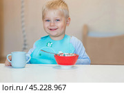 Baby food. Eating. Feeding the baby. A cute kid eats on his own with a spoon. Healthy eating. Family and children. Стоковое фото, фотограф Photojuli / Фотобанк Лори