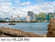 Nha Trang, Vietnam, 24 January 2024: Nha Trang's scenic coastline with rocky shore, and modern high-rise hotels. coast meets sandy haven, framed by contemporary architecture under Vietnamese sun. Стоковое фото, фотограф Павел Муравьев / Фотобанк Лори
