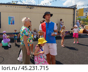 Coach of children's sports section communicates with parents. Children's sports festival in the street. (2024 год). Редакционное фото, фотограф Zima Nadezhda / Фотобанк Лори