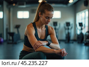 Женщина с фит-нес часами в спортзале. Стоковое AI-изображение, AI-художник Лара Богданова / Фотобанк Лори