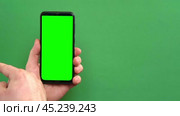 Young man hand use smartphone with green screen on green background. Gestures pack. Male hand touching, clicking, tapping swiping on black phone chromakey display. Close up Device. Modern Technology. Стоковое видео, видеограф Марина Демидюк / Фотобанк Лори