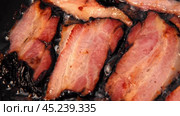 Frying Bacon Slices in a Pan. Crispy Pieces of Delicious Red Thin Smokey Bacon Fried in a Hot Skillet. Traditional Breakfast. Smoked Bacon Rasher or Strip Being Cooked. Grill. Fat High Calorie Food. Стоковое видео, видеограф Марина Демидюк / Фотобанк Лори