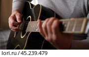 Playing the guitar. Strumming black acoustic guitar. Musician plays music. Man fingers holding mediator. Male hand playing guitar neck in dark room. Unrecognizable person rehearsing, fretboard closeup. Стоковое видео, видеограф Марина Демидюк / Фотобанк Лори