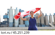 Sad young woman worker standing with big flag of Canada against background of factory. Стоковое видео, видеограф Яков Филимонов / Фотобанк Лори