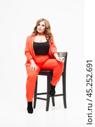 Plus size model with big breast and deep decollete, fat woman on white background in orange pantsuit, body positive concept. Стоковое фото, фотограф Станислав Тарко / Фотобанк Лори