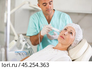 Elderly female client receiving hardware ultrasonic to revitalize and tighten facial skin at cosmetology clinic. Стоковое фото, фотограф Яков Филимонов / Фотобанк Лори