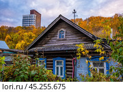 Деревенский дом на фоне современной многоэтажки на холме. Редакционное фото, фотограф Илья Старков / Фотобанк Лори