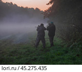 Охотник и егерь в тумане готовятся к стрельбе на опушке леса. Стоковое фото, фотограф Олег Елагин / Фотобанк Лори
