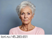 Unamused sad miserable mature caucasian woman wearing pink blouse, frowns face with dissatisfaction, sulks troubled as someone hurt her feelings. Indoor studio shot isolated on blue background. Стоковое AI-изображение, AI-художник Sergey Grishin / Фотобанк Лори