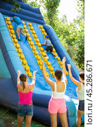 Two male friends climbing on inflatable slide with wooden poles. Стоковое фото, фотограф Яков Филимонов / Фотобанк Лори
