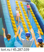 Happy young woman climbing on inflatable castle with wooden sticks. Стоковое фото, фотограф Яков Филимонов / Фотобанк Лори