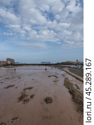 The aftermath of hurricane Dana in Valencia, Spain - Muddy river flowing through city after devastating flood in Valencia. Редакционное фото, фотограф Данил Руденко / Фотобанк Лори