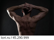 Handsome muscular bodybuilder posing on gray background. Low key studio shot. Стоковое фото, фотограф Станислав Тарко / Фотобанк Лори