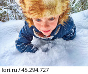 Disabled boy without an arm crawls through the snow while playing snowballs in winter in a snowdrift. The suffering of civilians in the war and confrontation between Ukraine and Russia. Стоковое фото, фотограф Кривошеина Елена Леонидовна / Фотобанк Лори