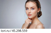 Portrait of young woman against a gray backdrop, her skin is glowing, making her the ideal subject for a cosmetic ad. Her natural beauty and tranquil demeanor are truly mesmerizing. Стоковое AI-изображение, AI-художник Павел Муравьев / Фотобанк Лори