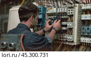 Electrician checking voltage of electrical cabinet. Стоковое AI-видео, аниматор Андрей Знаменский / Фотобанк Лори