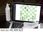 Chess task on laptop screen online. Near antibacterial spray and medical mask. Leisure in self-isolation. International chess day. Стоковое фото, фотограф Vadzim Yakubovich / Фотобанк Лори