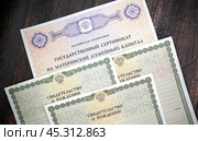 Сертификат на получение материнского капитала и свидетельства о рождении детей на темном фоне. Стоковое фото, фотограф Наталья Миронова / Фотобанк Лори