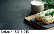 Вкусные эклеры с фисташковым кремом на каменной доске с чашкой кофе. Стоковое AI-изображение, AI-художник ФотоИнтеллект / Фотобанк Лори