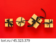 Black Friday. Sale of goods at reduced prices. Gift boxes made of eco-friendly kraft paper with discounted goods are marked with black bows on red background. Flat lay, copy space, top view, mock up. Стоковое фото, фотограф Виктория Катьянова / Фотобанк Лори