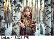 A beautiful girl in a traditional Russian folk shawl in a winter birch grove. The portrait symbolizes the traditions and beauty of the Russian people. Стоковое AI-изображение, AI-художник Photojuli / Фотобанк Лори