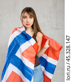 Sad young woman holding flag of Norway against unicoloured background. Стоковое фото, фотограф Яков Филимонов / Фотобанк Лори