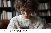 молодая девушка сосредоточена на смартфоне, преодолевая отвлекающие факторы и подавленность в помещении. Стоковое AI-изображение, AI-художник ФотоИнтеллект / Фотобанк Лори
